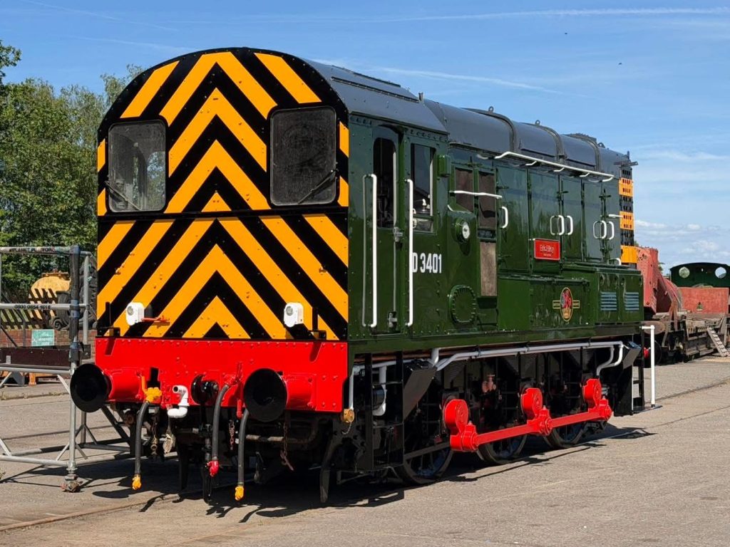 attYMRwb1sAD3gzCRkLAHlezVcgunqTgFW9Sn0SrkjWPUk - Midland Railway - Butterley Dark-green diesel locomotive on display with a high-contrast orange-and-black chevron pattern on the front and a bright red buffer beam underneath (loco P3401).