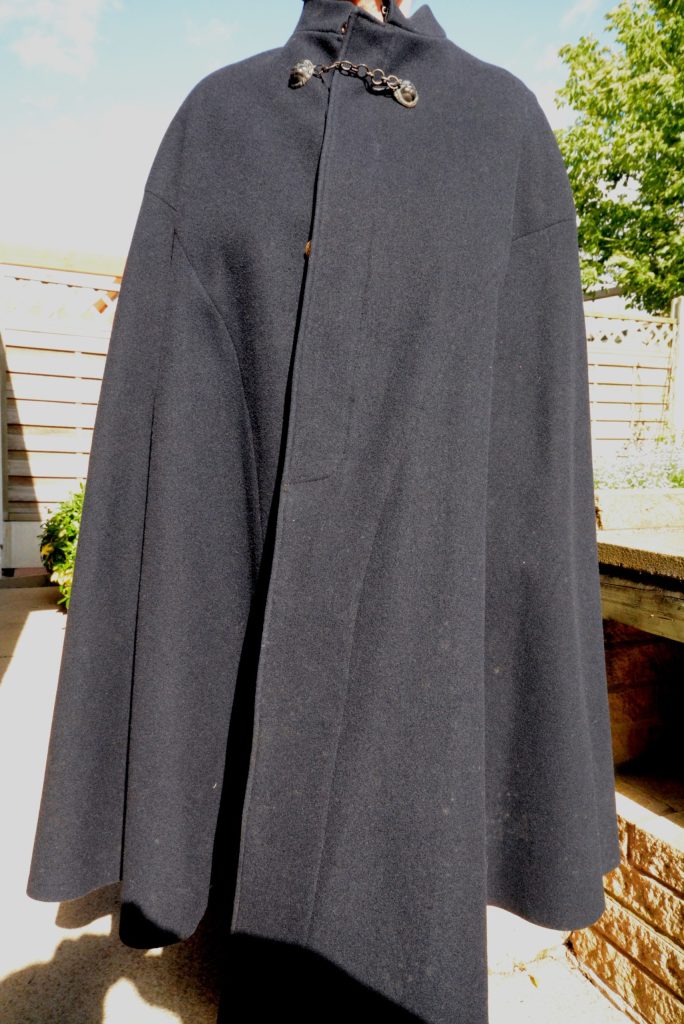 MR Policemans Cape - Midland Railway - Butterley Close-up of a person in a dark coat with a small decorative chain hanging from the pocket, outdoors.