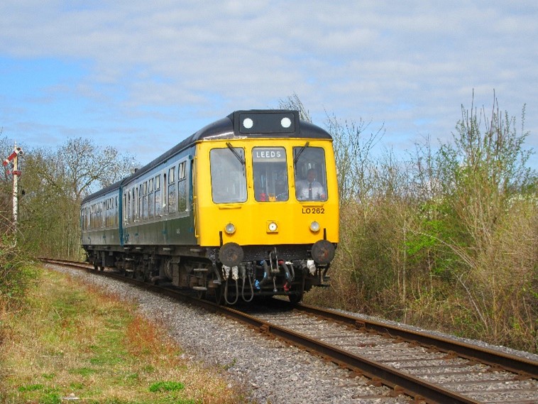 108 - Midland Railway - Butterley Leeds-bound yellow front diesel train on a rural railway track with foliage on either side.